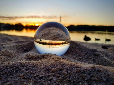 Brown transparent glass ball on the beach at sunset
